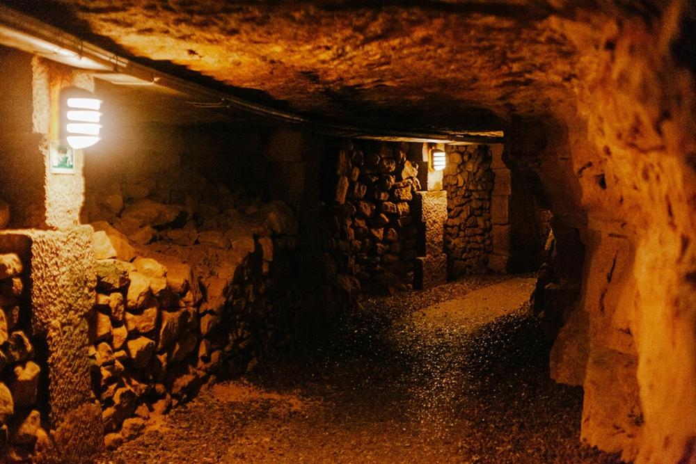 Illuminated underground tunnel in the Paris Catacombs, showcasing the eerie yet captivating atmosphere of the historic site