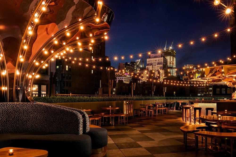 The Magic Hour Rooftop Bar & Lounge with string lights and a city skyline backdrop
