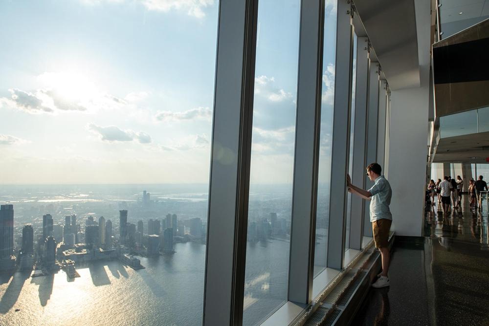 A man gazes out a window of the World Trade Center, overlooking the city skyline