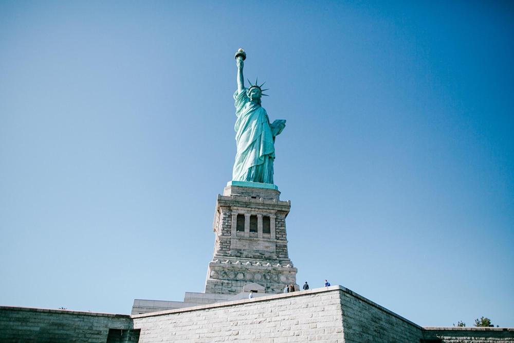 The Statue of Liberty stands tall amongst the clear blue sky