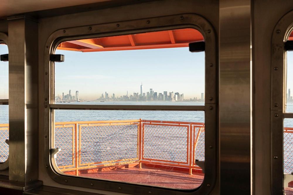 A view of the city skyline from the Staten Island ferry, showcasing tall buildings against a clear blue sky