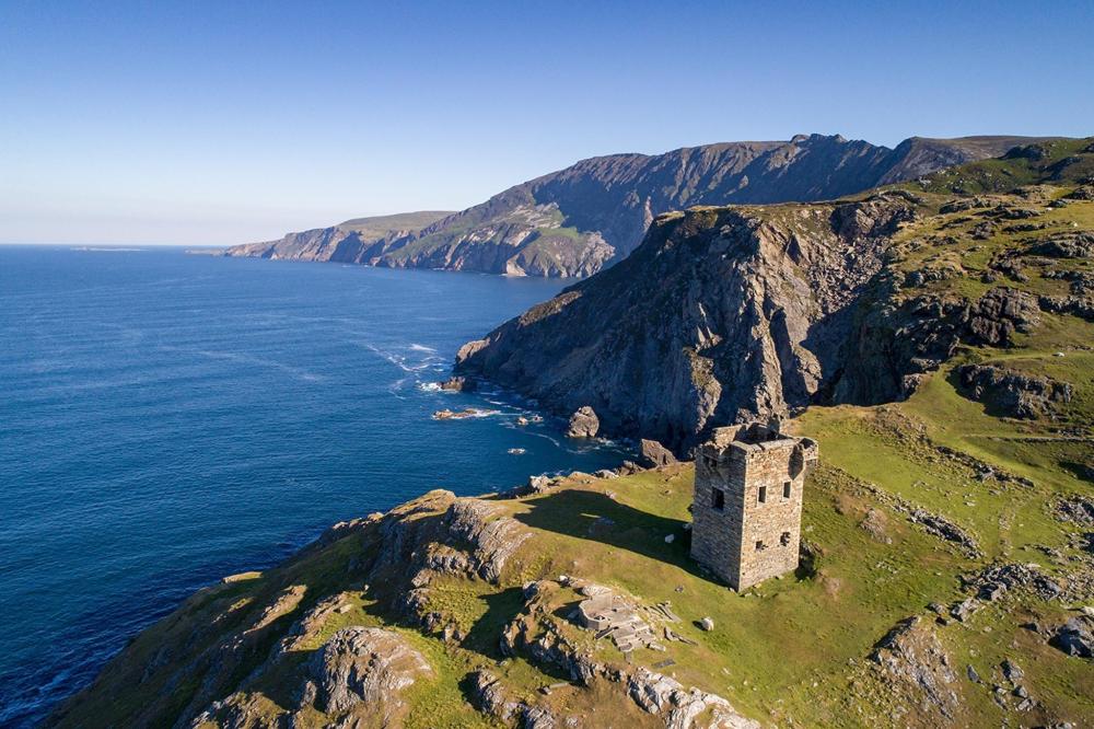 A small tower perched on a rocky hill, overlooking the vast ocean along Ireland's Wild Atlantic Way