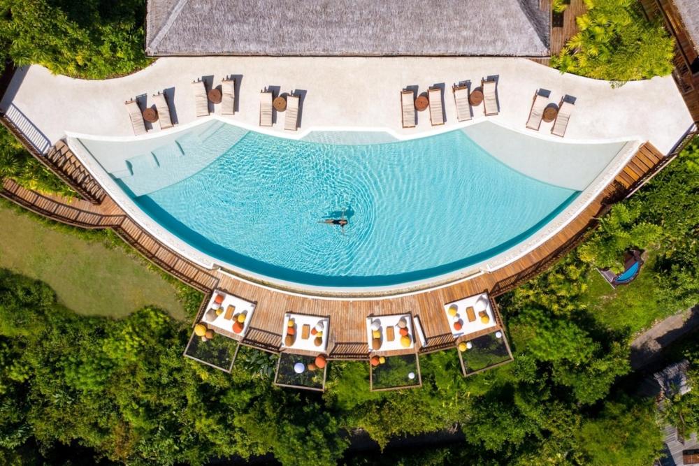 Aerial view of a serene pool nestled among trees at Six Senses Yao Noi, Thailand, showcasing natural beauty.