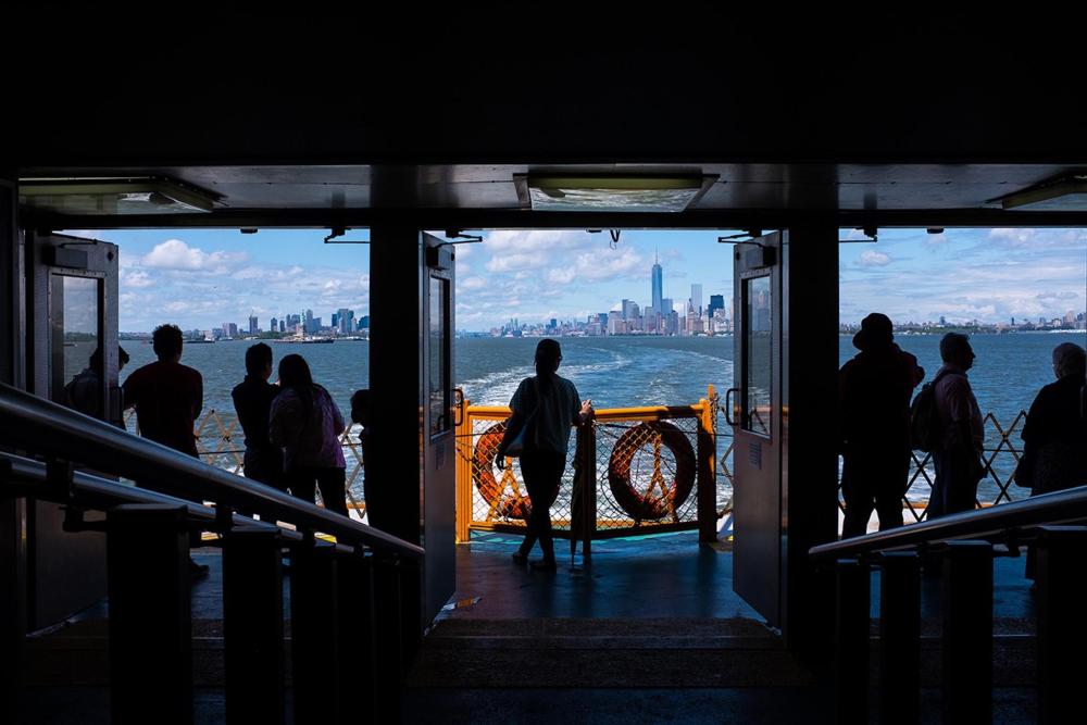 A group of people on the Staten Island Ferry gazing out at the water, enjoying the scenic view