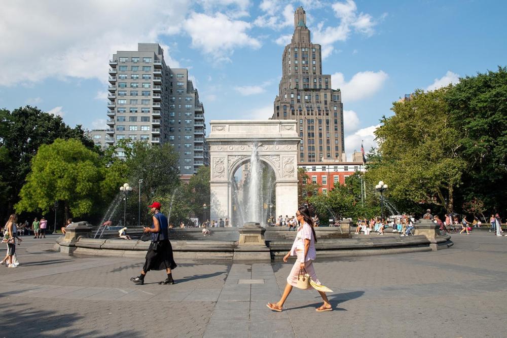 People stroll through a bustling street in the West Village, surrounded by urban architecture