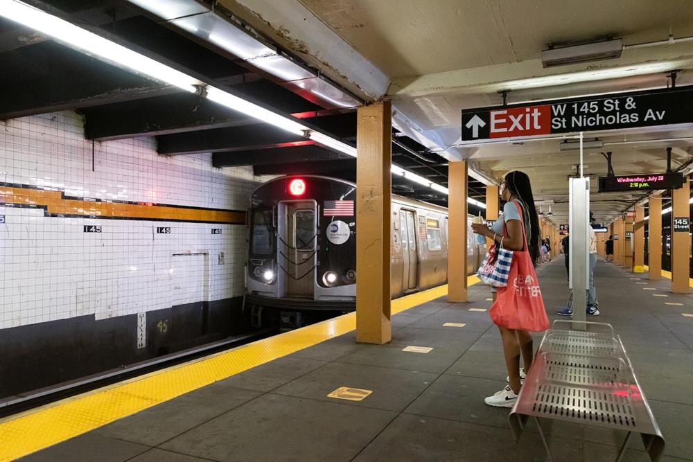 A woman stands on the subway platform, waiting for the train to arrive