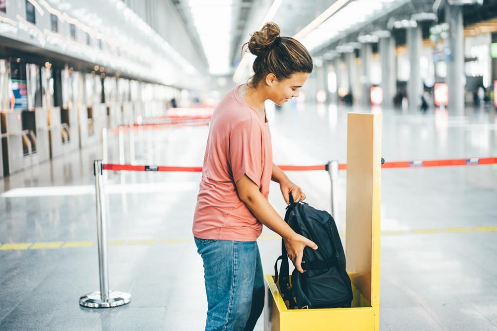 A woman in an airport measuring her luggage