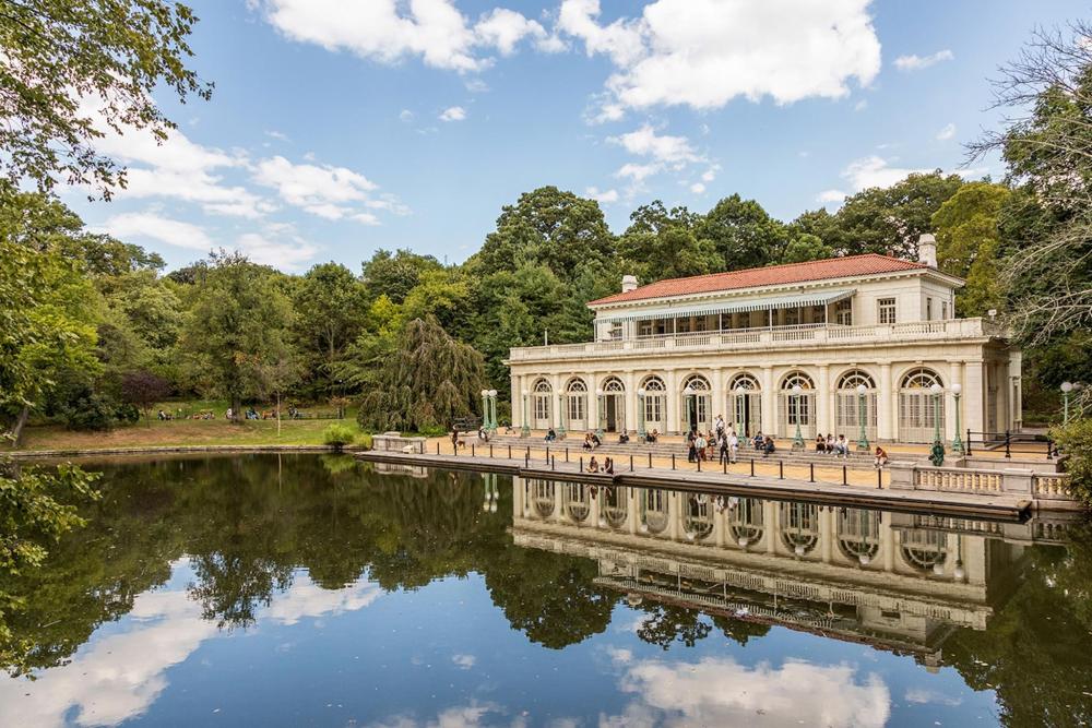 In Prospect Park, a large white building overlooks a pond, creating a scene of nature