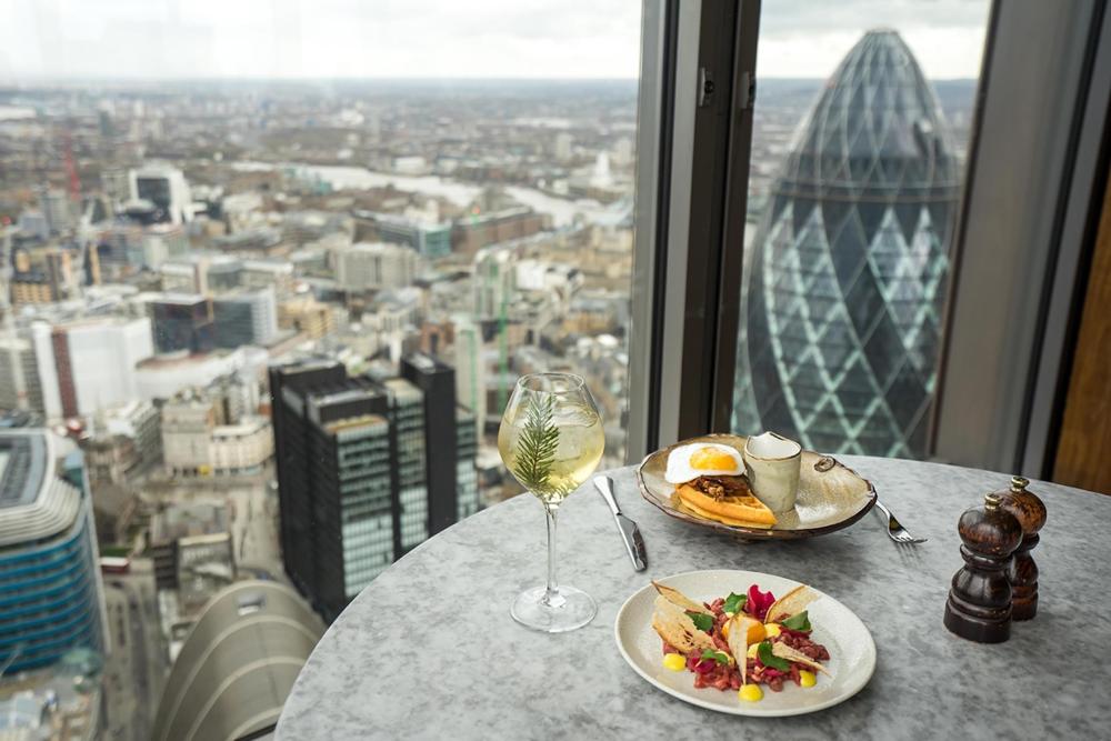 A beautifully set table in London featuring a plate of gourmet food and a spritz.