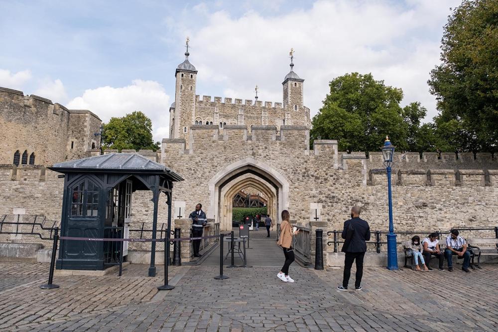 People stroll around the Tower of London, enjoying the historic architecture and vibrant outdoor atmosphere.