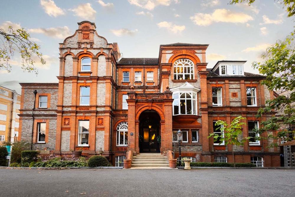 A large red brick hotel with numerous windows, known as Palmers Lodge Swiss Cottage in London.