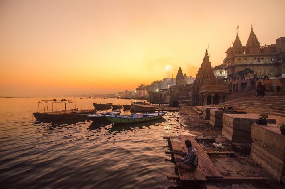 Boats docked on the water at sunset in Varanasi, creating a picturesque evening scene.