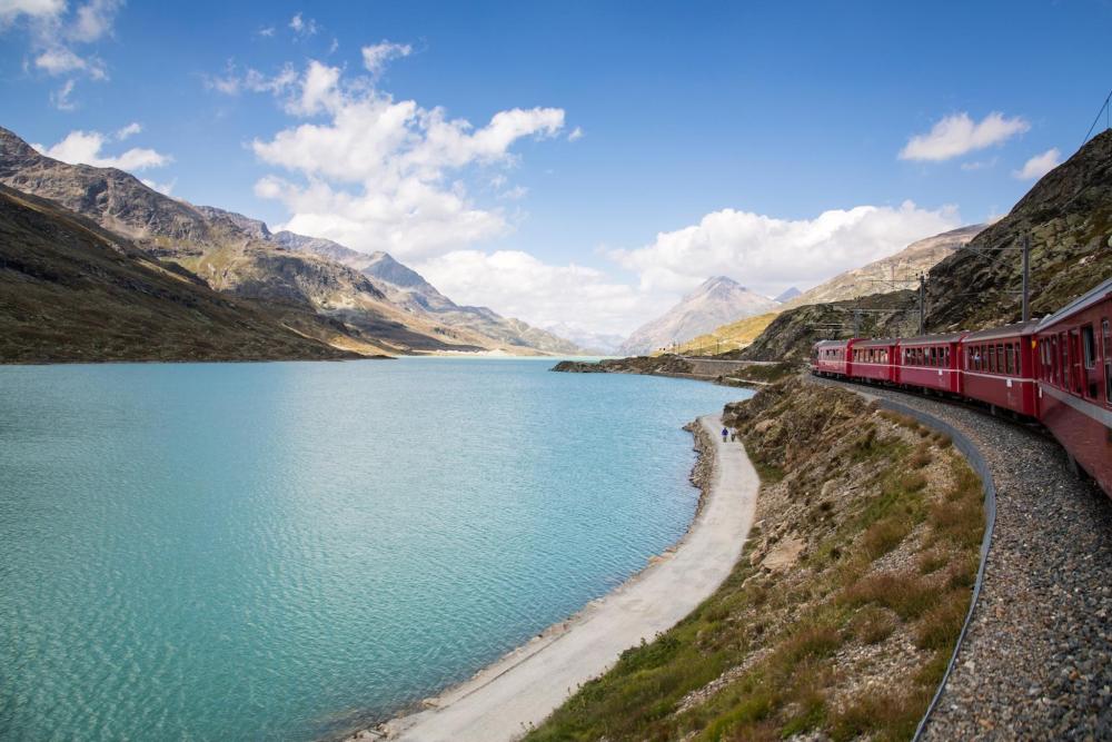 A train descends the mountainside near St. Moritz, showcasing stunning alpine scenery and a winding track.