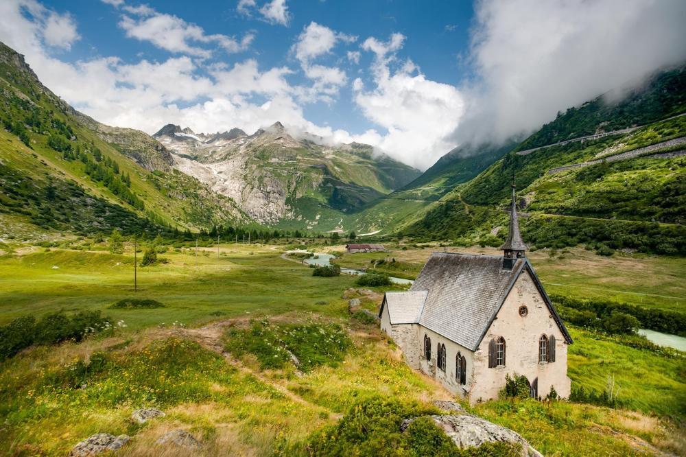 A small church nestled in the mountains, overlooking a serene valley below in Chur.