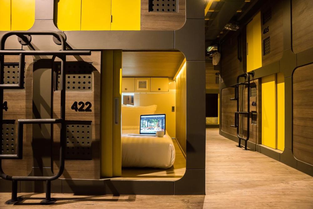 A Nonze capsule hotel room with yellow walls and wood floors, creating a welcoming atmosphere.