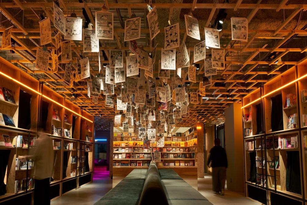Book And Bed Tokyo Shinjuku features a spacious library with tall shelves full of countless books, inviting readers to explore.