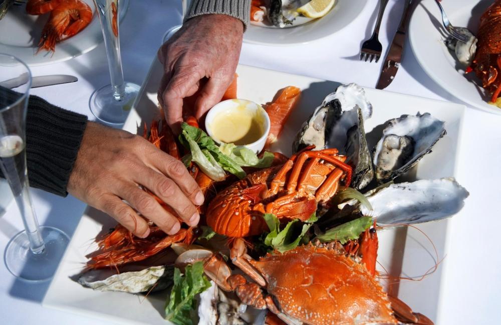 Some fresh seafood features on the table, with two hands ready to get stuck in