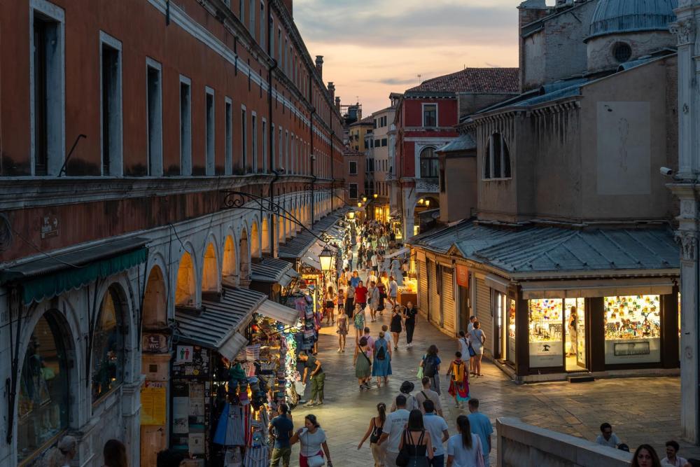 A busy street of Venice, with shop lights lining the path