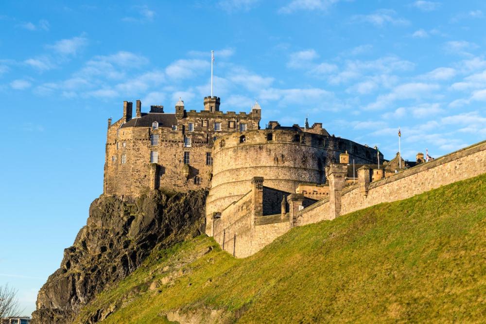 Edinburgh Castle depicted on a sunny day with little to no clouds in the sky