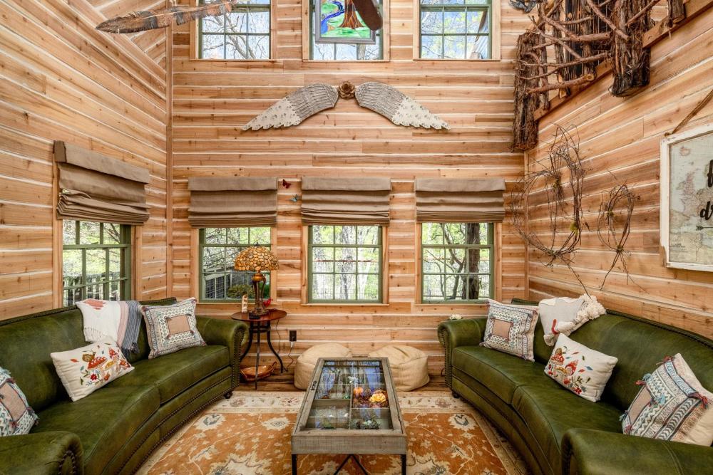 1. A cozy living room featuring a wooden ceiling and a comfortable couch, located in the Magical Treehouse, Texas.