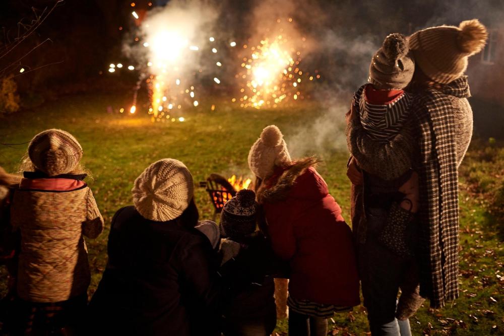 A family enjoys a vibrant display of fireworks against the night sky during Bonfire Night in the UK.
