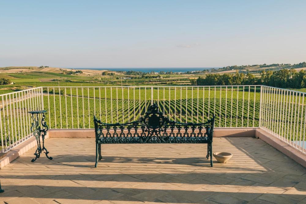 A charming bench on a balcony, offering a picturesque view of vineyards at La Forestiera Planeta Wine Resort, Sicily.