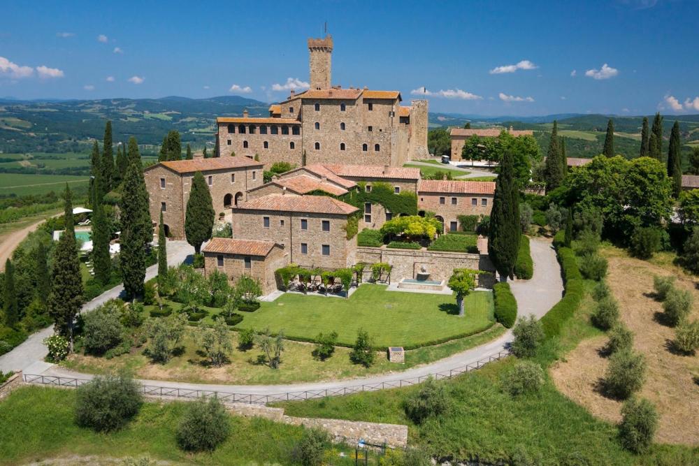 A picturesque view of Castello Banfi - Il Borgo, nestled among lush trees and rolling green hills.