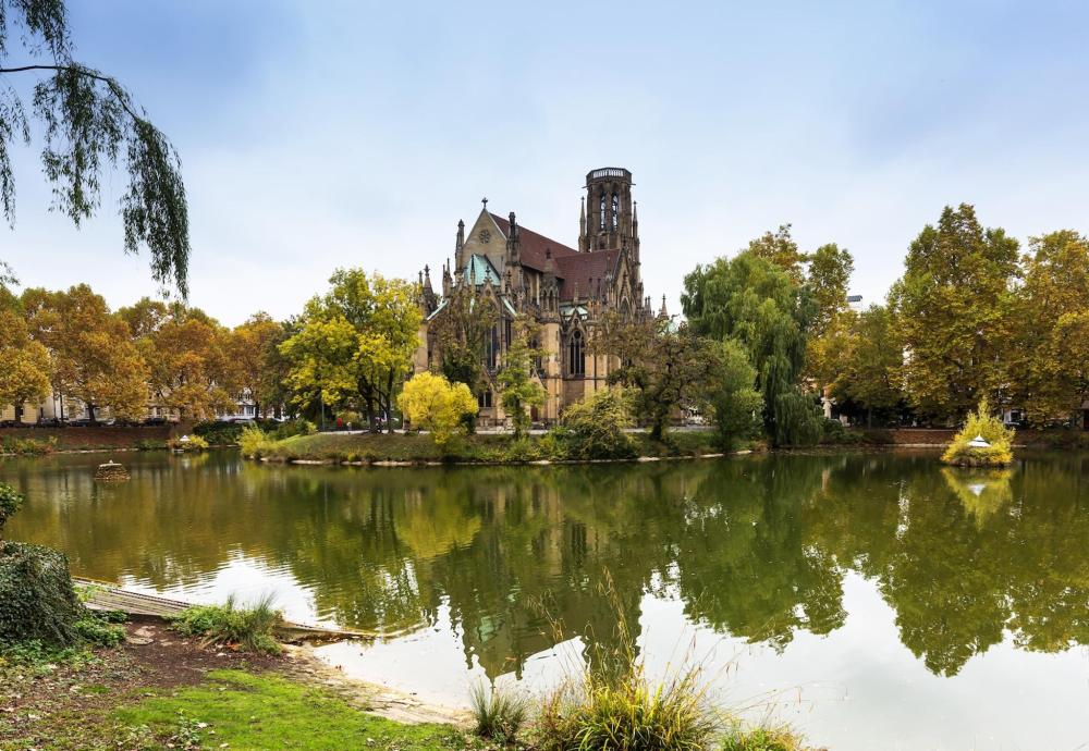 A large building with a tower in the background, overlooking a body of water in Stuttgart.