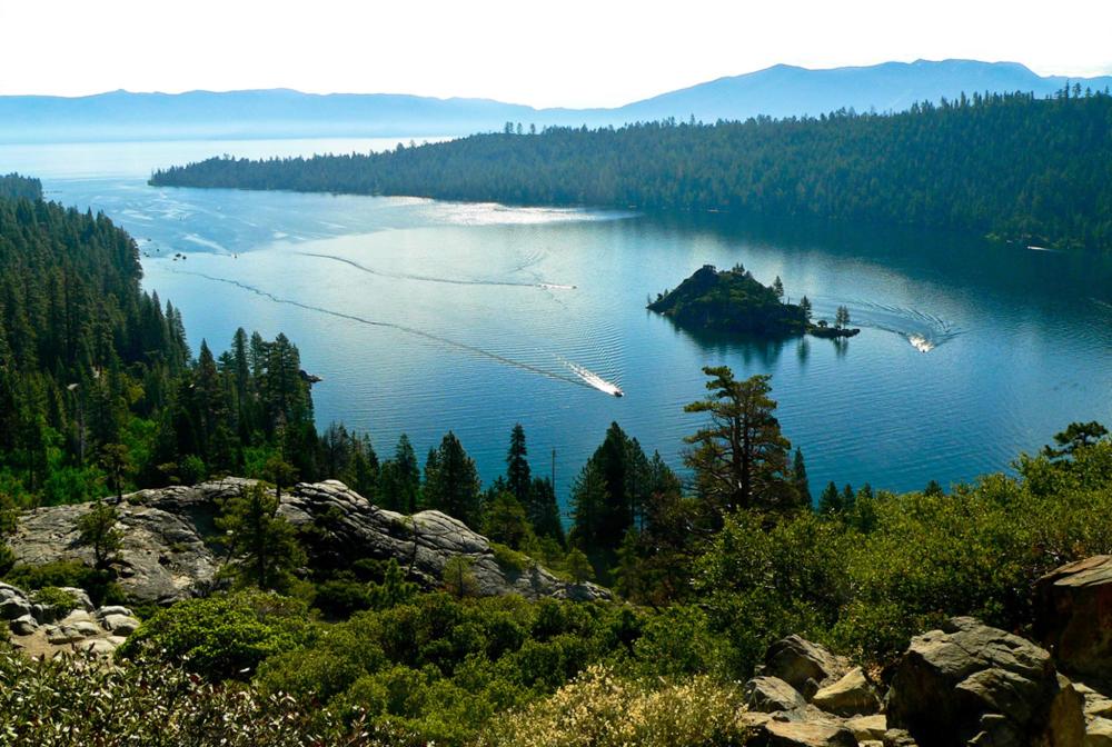 A peaceful vista of Lake Tahoe, California, displaying its clear blue waters embraced by vibrant green forests.