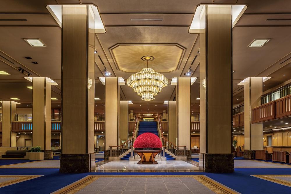 A spacious lobby at the Imperial Hotel Tokyo featuring an elegant chandelier and a grand central table.