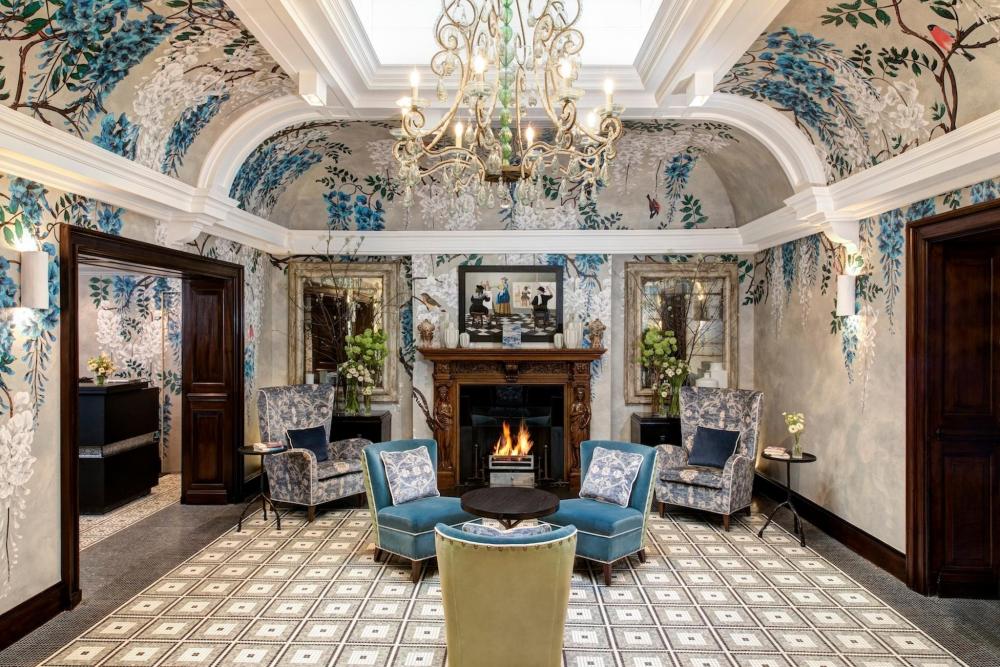  The lobby of Brown's Hotel features elegant blue floral wallpaper, creating a warm and inviting atmosphere for guests.
