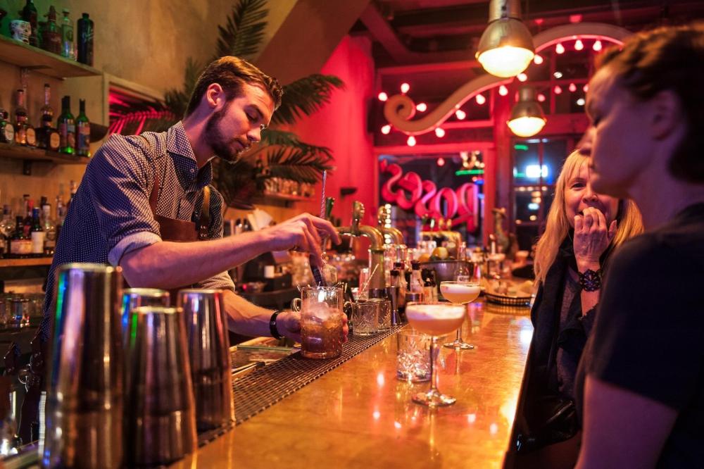 A bartender prepares drinks at a lively bar in Amsterdam, showcasing a vibrant nightlife atmosphere