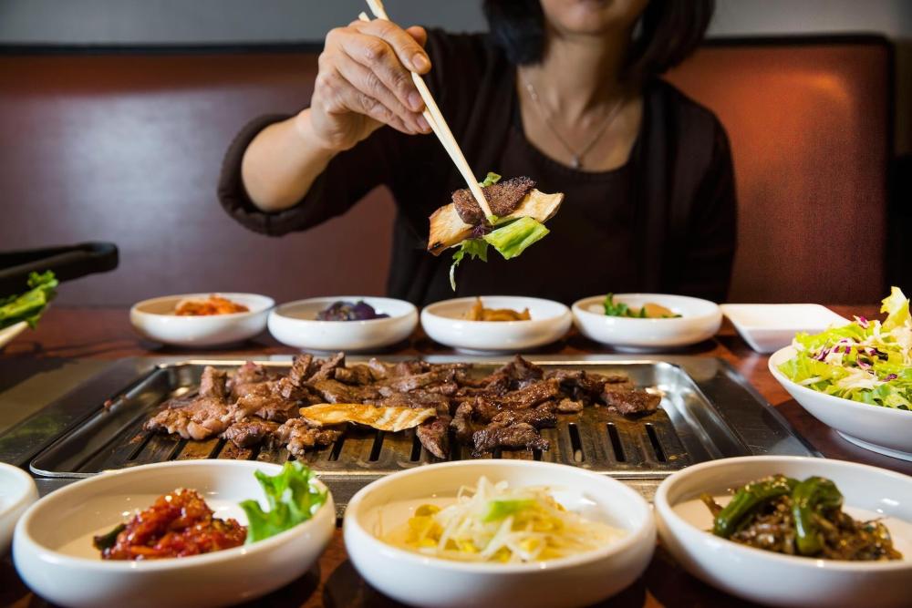 Someone prepares food on a grill for a DIY BBQ in South Korea, showcasing vibrant ingredients