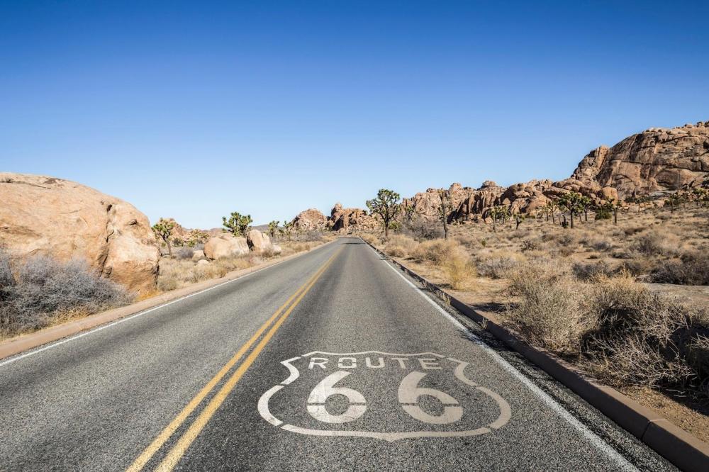 A road featuring a painted Route 66 sign, symbolising the historic highway and American road trip culture