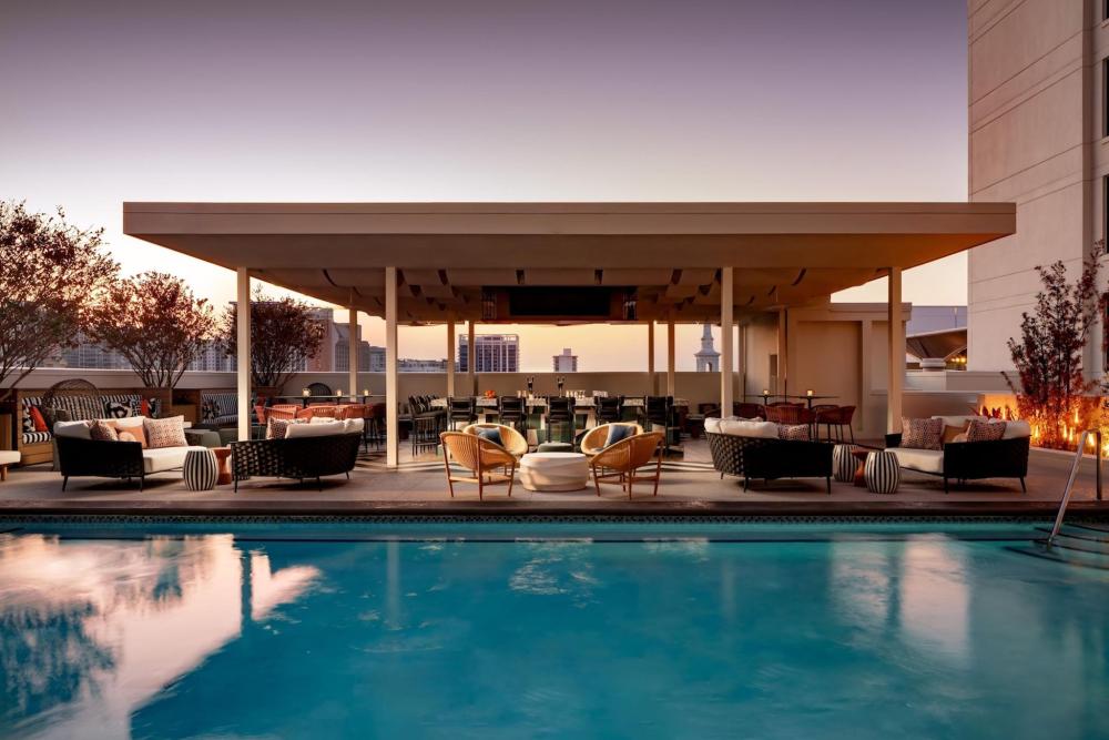 The pool area at the Grand Bohemian Orlando, Autograph Collection, featuring chairs and trees under a clear purple-yellowish sky