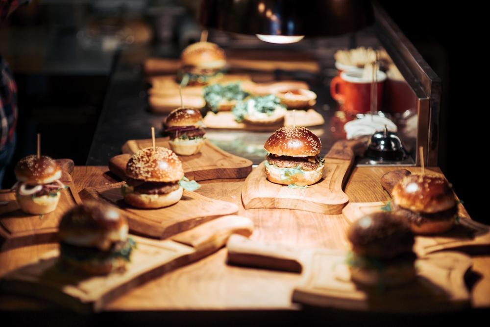 A dimly lit table filled with various hamburgers, ready for a meal
