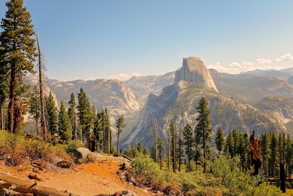 A panoramic view of Half Dome from the summit of a mountain in Yosemite, California, showcasing the stunning landscape