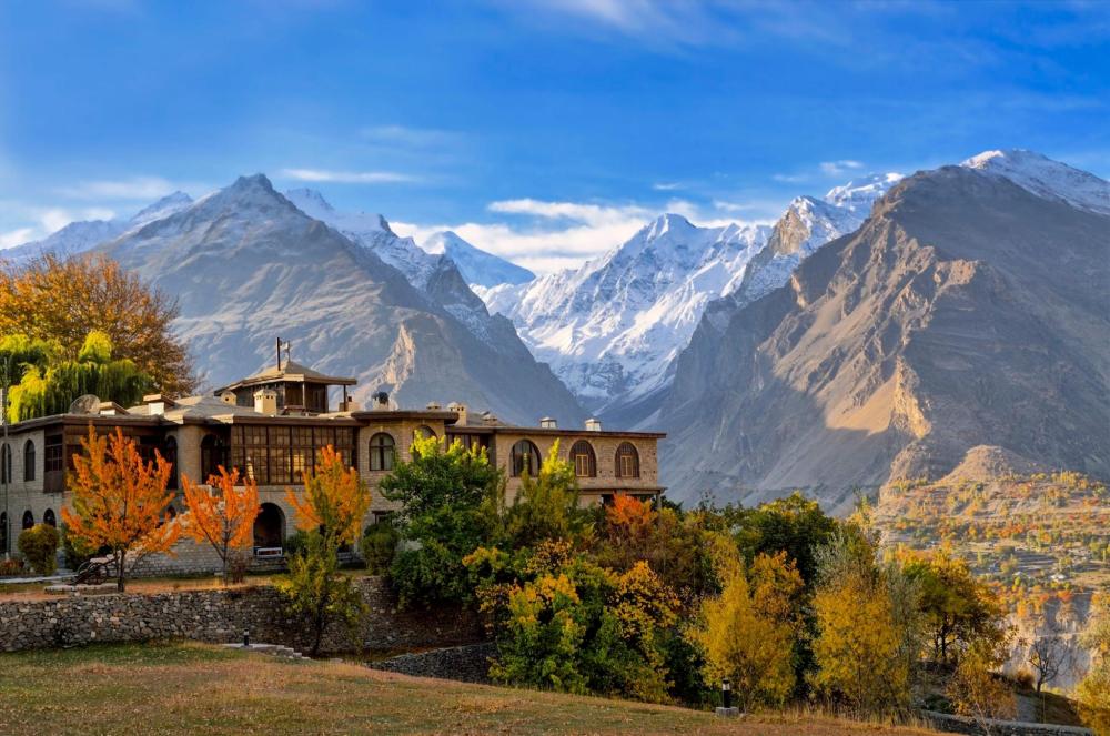 A large stone building nestled in the mountains of Hunza Valley, Pakistan, with a majestic mountain rising in the background