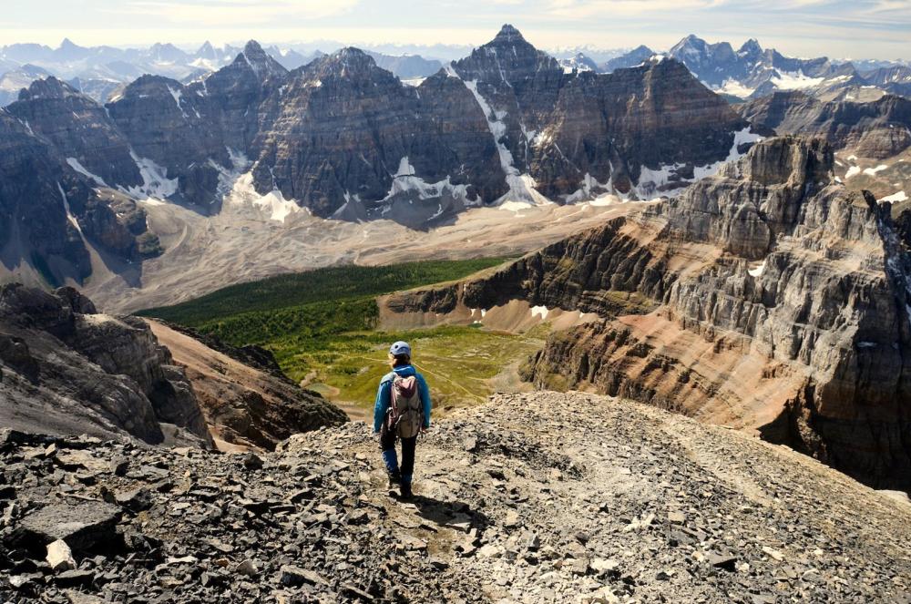 A hiker stands on the edge of a mountain in the Valley of the Ten Peaks, surrounded by stunning mountain scenery in Canada