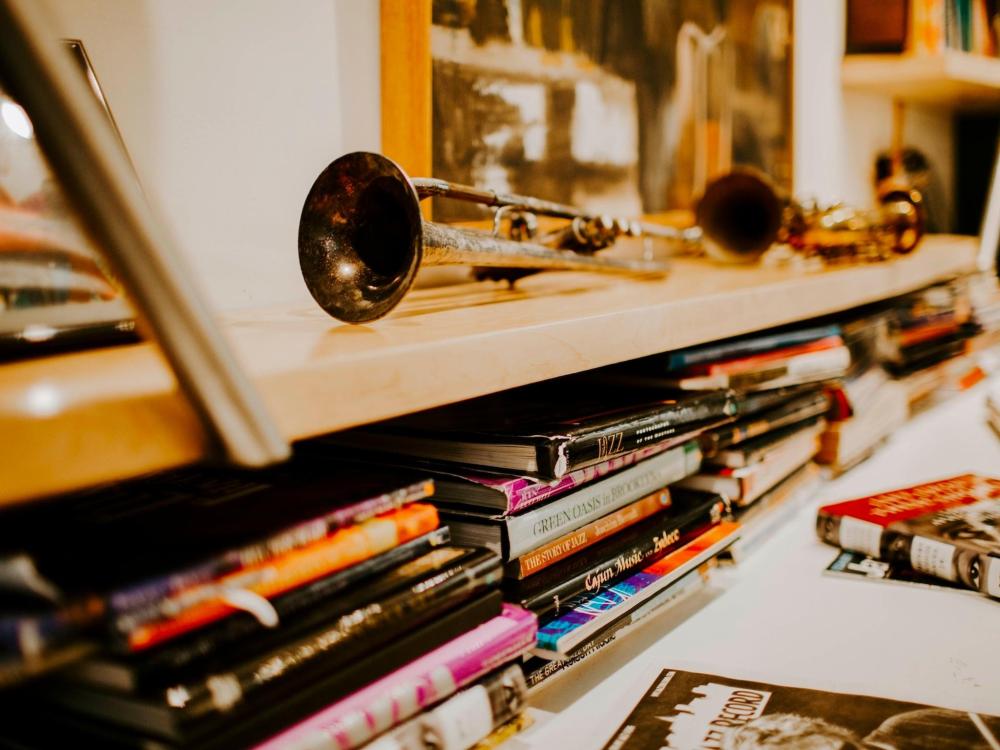 A shelf displaying various books alongside music equipment, including speakers and a turntable