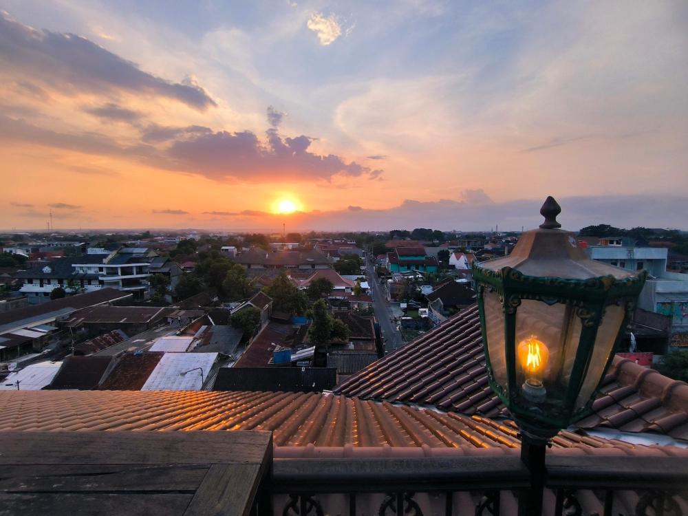The sun sets over Prawirotaman city, casting a warm glow beside a lamp post