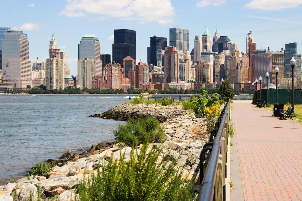View of the city skyline from Liberty State Park, showcasing tall buildings against a clear blue sky