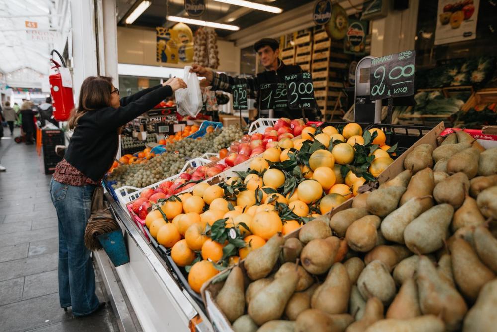 A woman purchases fresh fruit at Nuovo Mercato di Testaccio in Testaccio, surrounded by vibrant market stalls