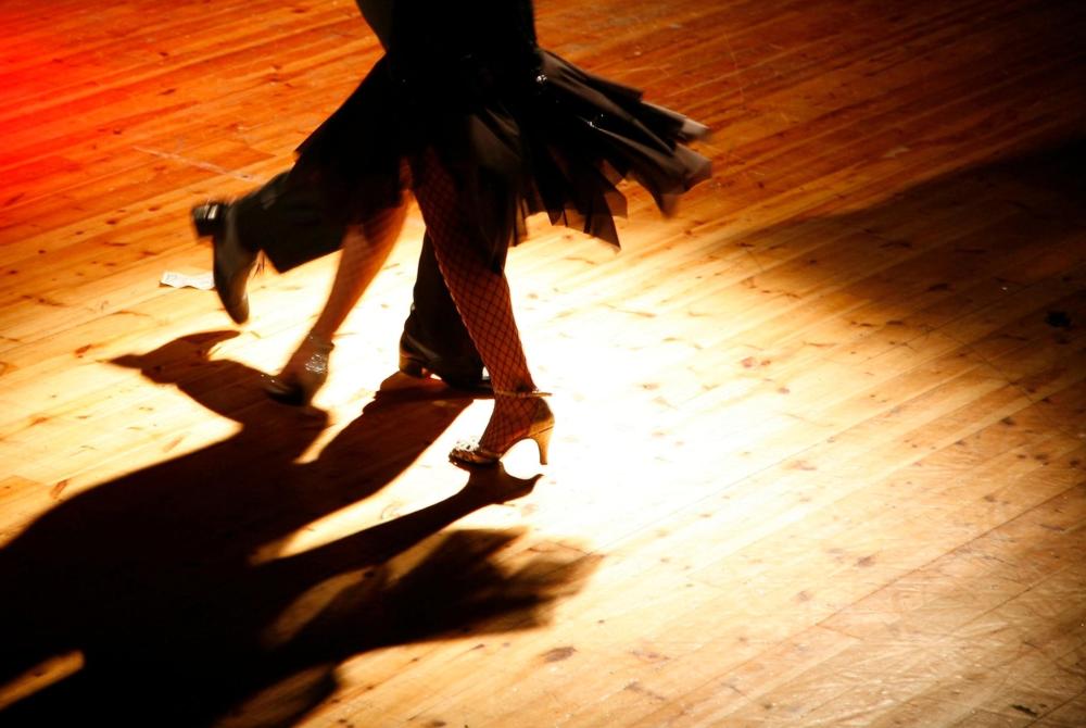 A couple dancing salsa on a wooden floor, showcasing vibrant movements in a lively Colombian setting