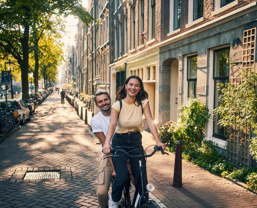 A couple biking on a vibrant street, surrounded by city scenery