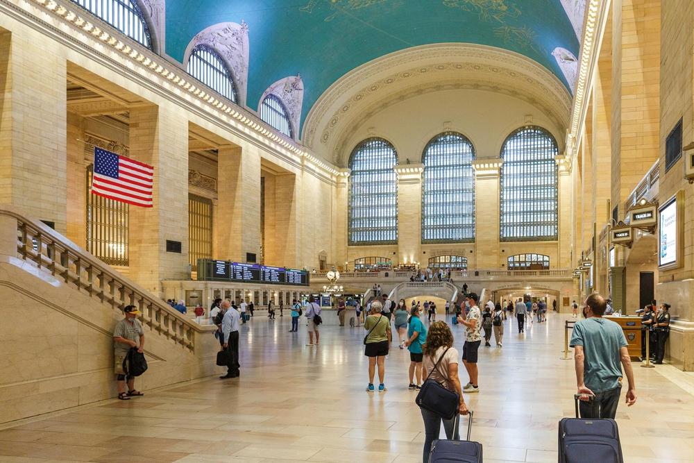 A large crowd of people walking around Grand Central Station, showcasing its architectural grandeur