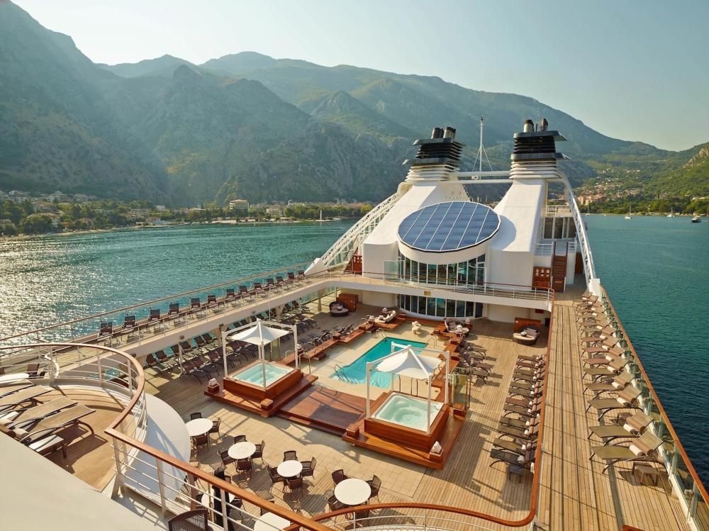 The top deck of a Seabourn cruise ship featuring a pool surrounded by lounge chairs and ocean views