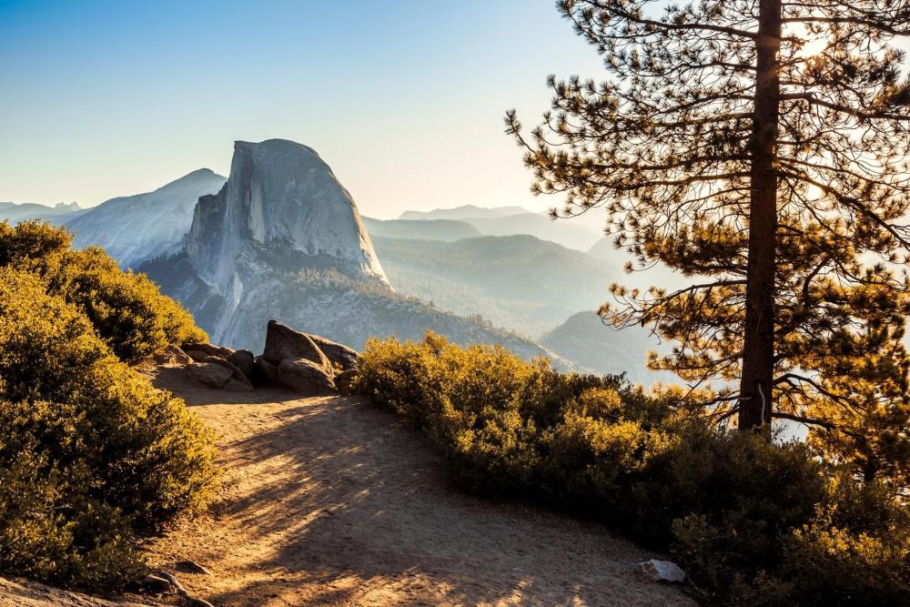 Half Dome in Yosemite National Park, California, is depicted. Its iconic shape stands strongly against a vibrant backdrop.