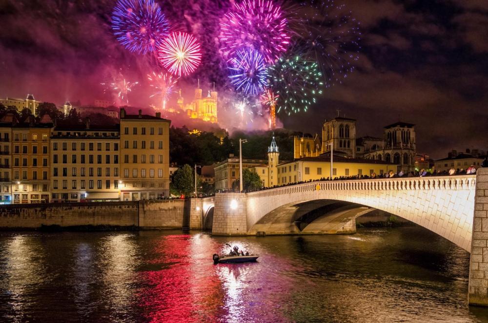 Fireworks illuminate Lyon's River Saône, creating a vibrant display against the night sky.