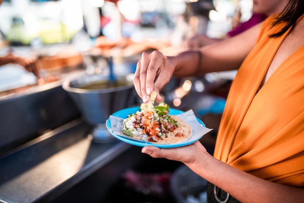 A woman presents a beautifully arranged plate of food, embodying the essence of a fine dining moment.